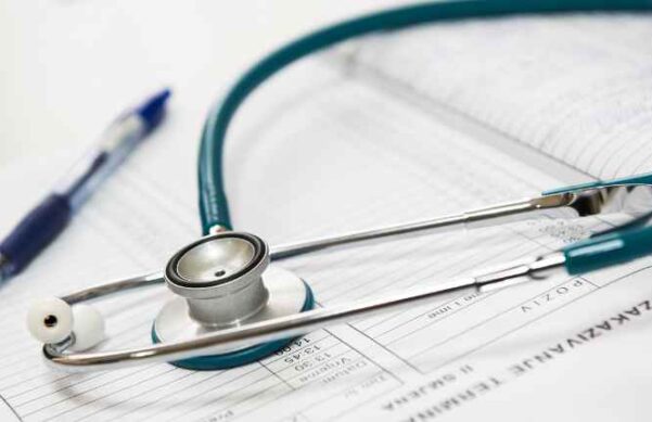 stethoscope over a book with blue pen in the background.