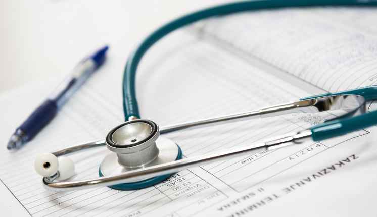 stethoscope over a book with blue pen in the background.