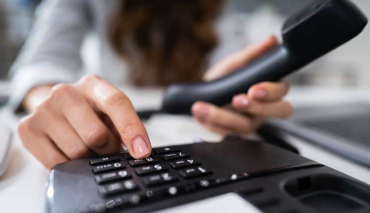 Landline telephone with person's fingers pressing the buttons