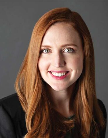 A person with long red hair smiling