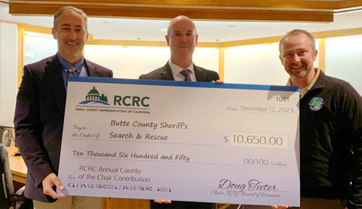 Three men holding a large check