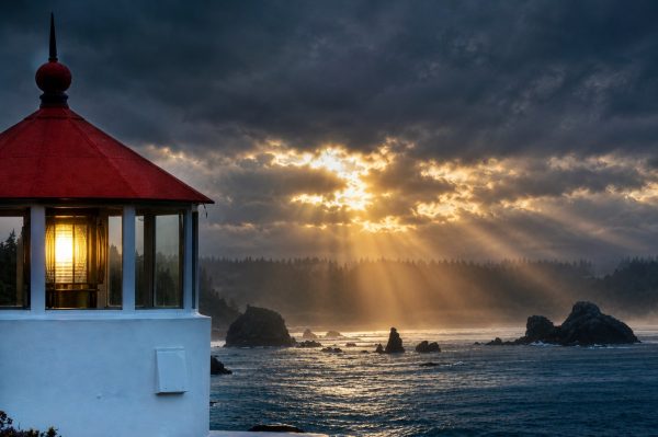 Attachment-1-First-Place-Photo-by-Ashley-Fox-Humboldt-County Red and white lighthouse with ocean and sun peaking through clouds