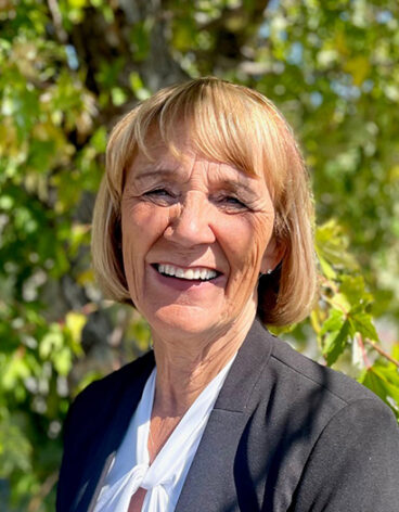 Person smiling in front of trees