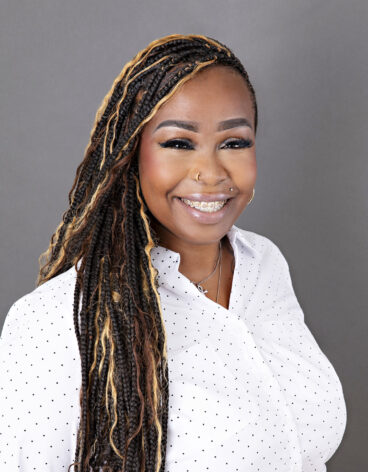 Woman smiling with long dark hair and a white blouse.
