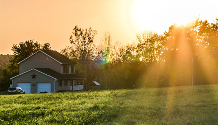 A house with sun shining through the trees.