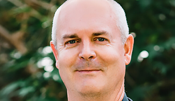 Person smiling in front of trees