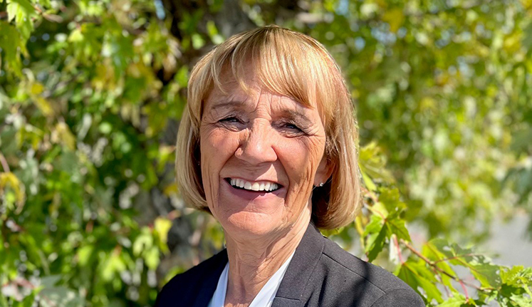 Person smiling in front of trees
