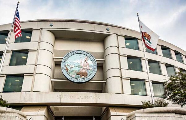 Building of the CPUC with California State Seal affixed on front and American and State flags to the side of the entrance