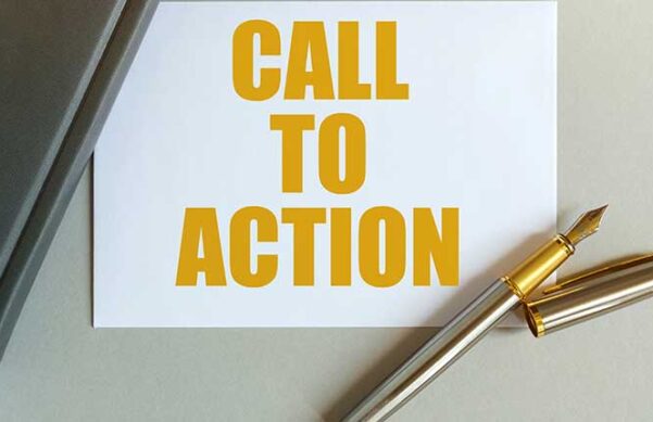paper with yellow lettering under the corner of a laptop and a pen