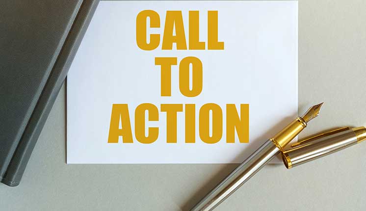 paper with yellow lettering under the corner of a laptop and a pen