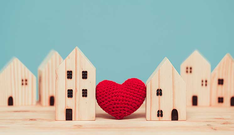 display of small wooden houses with a crocheted heart between them