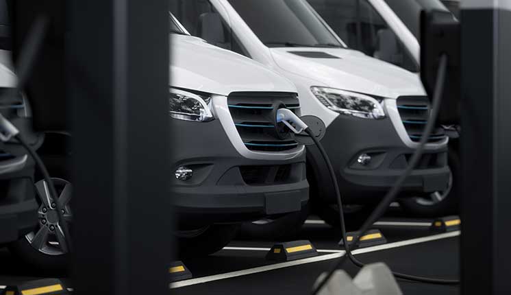 vans plugged into electric vehicle charging stations