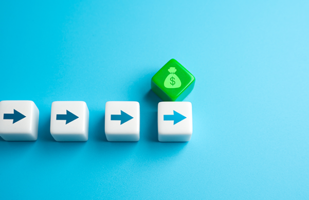 five dice on blue background. four dice in straight line with arrows pointing right and one die, green with money bag etched on it, resting above the last arrow