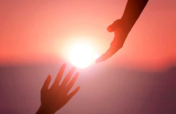 hands reaching for each other against a sunset backdrop