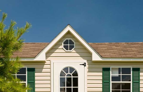 yellow house with tree on left side against the backdrop of the blue sky