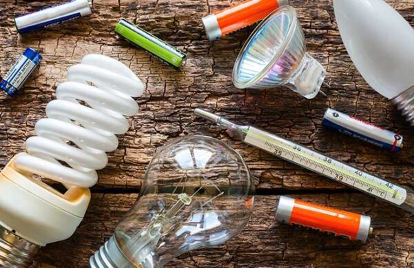 lightbulbs batteries and thermometer scattered on wooden table