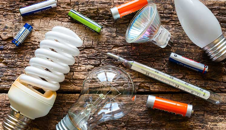 lightbulbs batteries and thermometer scattered on wooden table