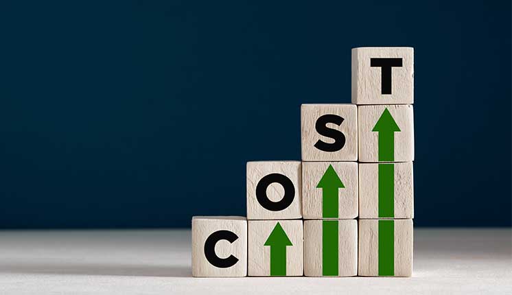blocks with the letters C-O-S-T sitting on top of upward facing green arrows