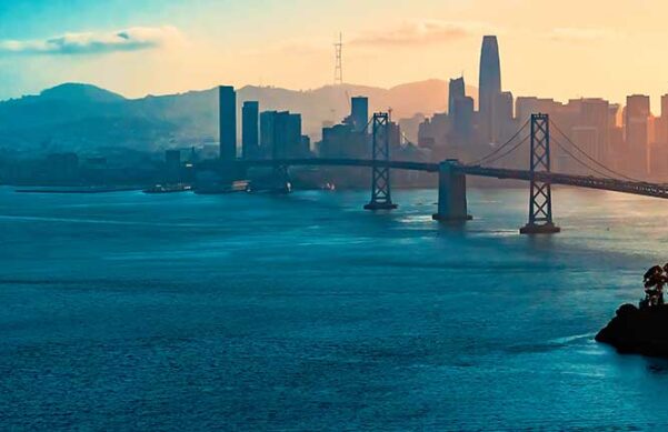 water of a bay with bridge and cityscape in the background