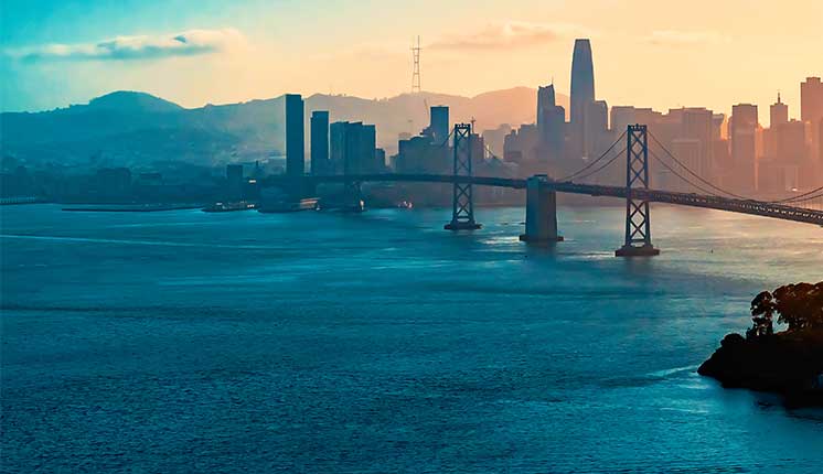 water of a bay with bridge and cityscape in the background