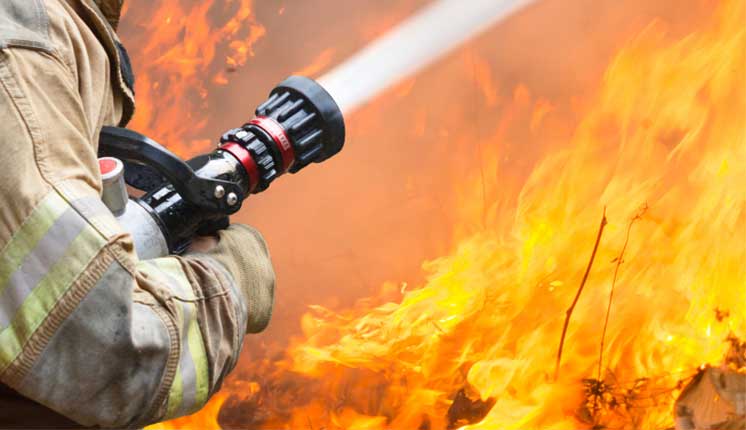 firefighter with hose fighting wildfire