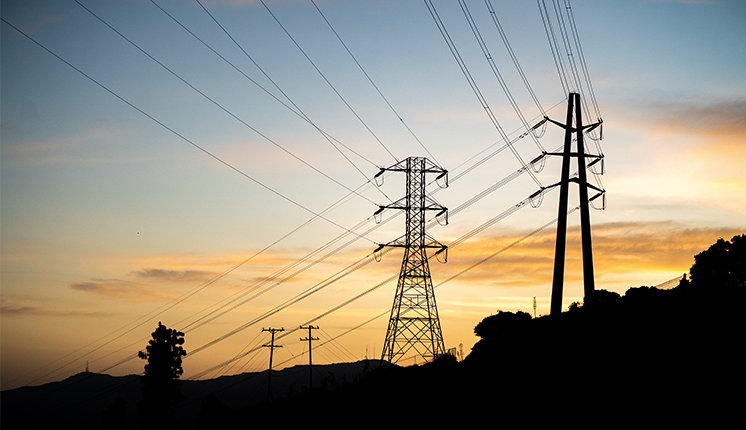 telephone lines in an uninhabited landscape against a blue sky and fading yellow sun.