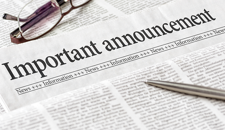 glasses and a pen resting on a newspaper with headline reading "Important Announcement"