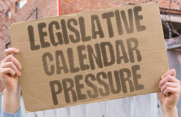 hands holding up cardboard sign with black block letters on it