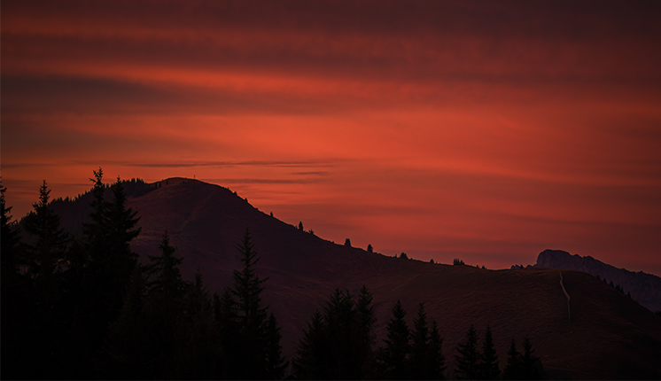 red sky backdrop against rolling peaks.